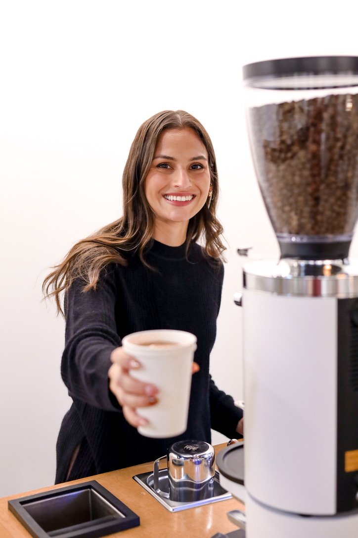 Silk Road barista handing a fresh cup of coffee across the bar